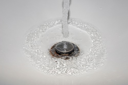 Water rushing down the plughole in a ceramic sink